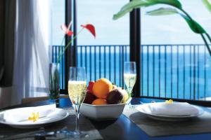 Moon Ocean Ginowan Hotel & Residence في غينوان: طاولة مع وعاء من الفاكهة وكؤوس من الشمبانيا