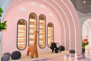 a room with a pink wall with giraffes and elephants at The Qube Hotel Shanghai Sanjiagang - Offer Pudong International Airport and Disney shuttle in Shanghai
