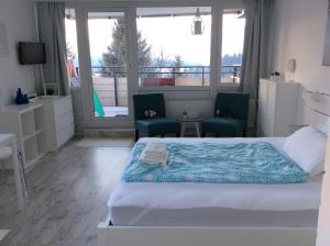 a bedroom with a bed and two chairs and a window at Wellness Apartment Sankt Englmar in Sankt Englmar +52 photos