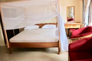 ein Schlafzimmer mit einem Himmelbett und einem Stuhl in der Unterkunft A wonderful Beach property in Diani Beach Kenyaa dream holiday place in Mombasa
