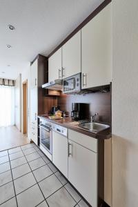 uma cozinha com armários brancos e um lavatório em Haus Seemuschel _ Fewo 4 em Cuxhaven