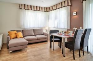 uma sala de estar com um sofá, uma mesa e cadeiras em Haus Seemuschel _ Fewo 4 em Cuxhaven