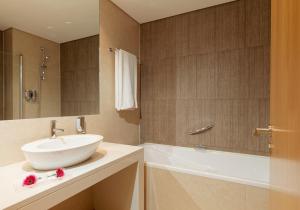 a bathroom with a white sink and a bath tub at Mercure Lisboa Almada in Almada