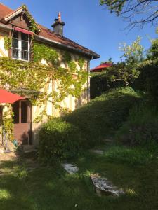 L'Atelier du Paysagiste - maison d'artiste في جيفرني: منزل مغطى ivy مع مسار يؤدي إلى ذلك
