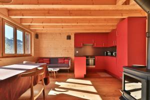 una cocina con armarios rojos y una mesa en una habitación en Comfortable chalet in the heart of nature, calm and peaceful en Saint-Luc