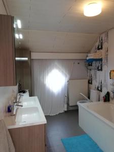 een badkamer met 2 wastafels, een bad en een bad bij CASA Victoria in Kuringen