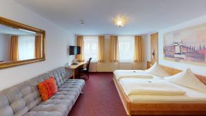 ein Hotelzimmer mit zwei Betten und einer Couch in der Unterkunft Blochums Gasthof Hirsch in Marktoberdorf
