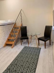 Zimmer mit 2 Stühlen, einem Tisch und einem Bett in der Unterkunft W19 Apartments in Miskolc