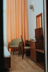 Zimmer mit orangefarbenem Vorhang, Schreibtisch und Stuhl in der Unterkunft Hotel Central in Osijek