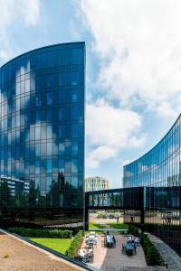 un bâtiment en verre avec des tables devant lui dans l'établissement Airport Plaza Hotel Hamburg, à Norderstedt