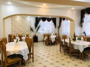 un restaurante con mesas y sillas blancas y ventanas en Pensiunea Valurile Bistritei en Vatra Dornei