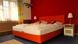 a large bed in a room with a red wall at Boutiquehotel Goldene Rose in Rothenburg ob der Tauber