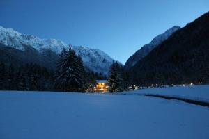 a snow covered field with a house in the mountains at Chalet Presanella in Temù