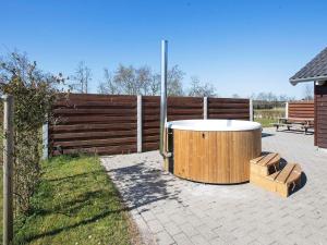Un bain à remous en bois est installé à côté d'une clôture. dans l'établissement 8 person holiday home in Idestrup, à Bøtø By