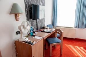 um quarto com uma secretária, uma ventoinha e uma cadeira. em Flair Hotel Deutsches Haus em Arendsee