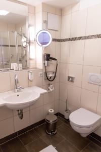 a bathroom with a sink and a toilet and a mirror at Flair Hotel Deutsches Haus in Arendsee