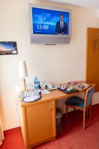 Habitación con escritorio y TV en la pared. en Flair Hotel Deutsches Haus en Arendsee