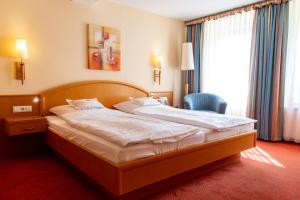 a bedroom with a bed and a chair and a window at Flair Hotel Deutsches Haus in Arendsee