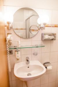 ein Bad mit einem Waschbecken und einem Spiegel in der Unterkunft Flair Hotel Deutsches Haus in Arendsee