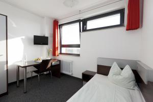 una camera con letto, scrivania e tavolo di Jugendherberge City-Hostel Köln-Riehl a Colonia