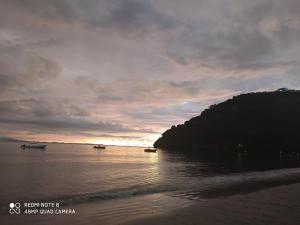 - une plage avec des bateaux dans l'eau au coucher du soleil dans l'établissement Bungalows des tropiques, à Nosy Be