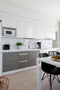 a kitchen with white cabinets and a table with a plate of food at SleepWell Apartments Itäkeskus, close to metro in Helsinki