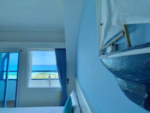 a bedroom with a window and a boat on the wall at Hotel Bayview in Dahan