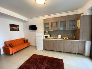 cocina con sofá naranja y nevera blanca en Apartament Ella D25 Mackerel, en Mamaia Nord – Năvodari