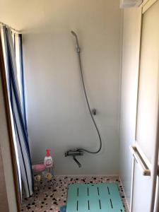 a shower in a bathroom with a tiled floor at Guest House Hostel yukuru in Iiyama