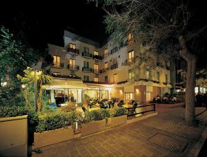 un bâtiment la nuit avec des personnes assises devant lui dans l'établissement Hotel Ondina, à Cattolica