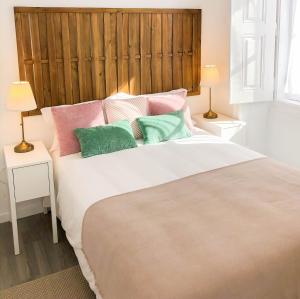 1 dormitorio con 1 cama grande y almohadas coloridas en Casa dos Castelos en Évora