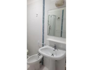 ein weißes Badezimmer mit einem Waschbecken und einem Spiegel in der Unterkunft BA - Cristallo - Sea View - in Lignano Sabbiadoro