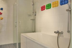 Un baño blanco con ducha y bañera. en Duinerei 2, en Callantsoog 12 fotos más