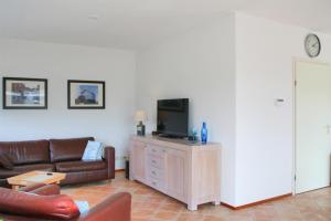 een woonkamer met een bank en een flatscreen-tv bij Kruisweg 4 in Callantsoog