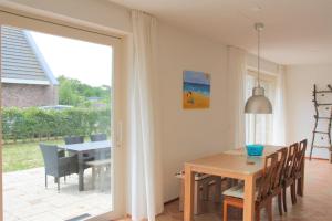 een eetkamer met een tafel en een glazen deur bij Kruisweg 4 in Callantsoog