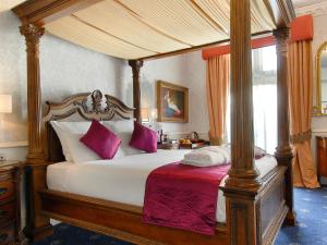 een slaapkamer met een hemelbed met paarse kussens bij Grand Royale Hyde Park in Londen