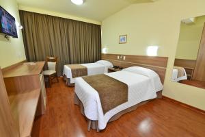 a hotel room with two beds and a mirror at Curi Palace Hotel in Pelotas