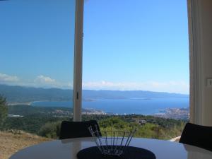 una mesa con sillas y vistas al agua en Gîtes Sassone, en Alata