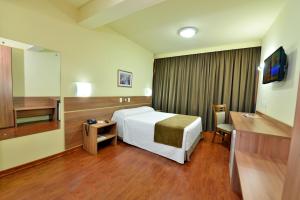 Habitación de hotel con cama y escritorio en Curi Palace Hotel, en Pelotas