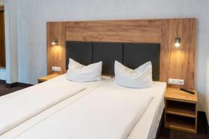 um quarto com 2 camas e almofadas brancas em Hotel Fischertor em Augsburg