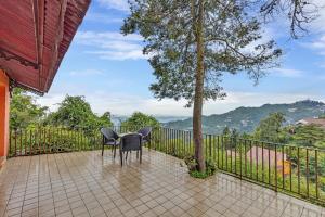 a table and chairs on a balcony with a tree at Club Mahindra Mussoorie in Mussoorie