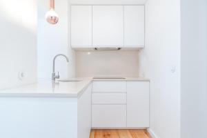 een witte keuken met witte kasten en een wastafel bij Casa Boma Lisboa - Charming and Typical Apartment - Lapa III in Lissabon