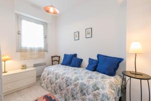 a bedroom with a bed with blue pillows and a window at KER HEDWIGE in Carnac