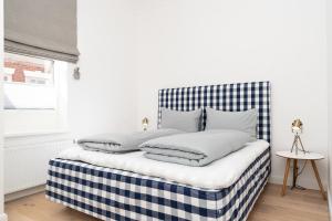 a bed with a blue and white checkered headboard at Meer-Lust-Sylt Haus Christiansen in Westerland