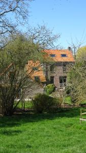 a house with an orange roof on a green field at La Miellerie in Huppaye