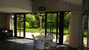 sala de estar con mesa, sillas y puertas correderas de cristal en La Miellerie en Huppaye