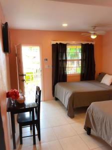 a bedroom with two beds and a table and a window at Tropical Paradise in Caye Caulker
