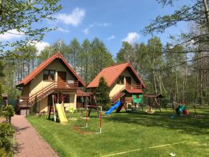 a house with a playground in the yard at Agroturystyka Źródełko in Święta Katarzyna