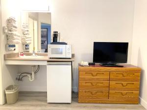 a bathroom with a sink and a television on a dresser at Super 8 by Wyndham Sicamous in Sicamous