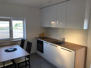 a kitchen with white cabinets and a table and a sink at Villa Ievyne 2 in Paežeriai